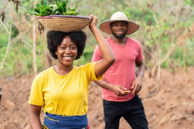 Afrikalı çiftçi sebze ve çapa taşıyor.