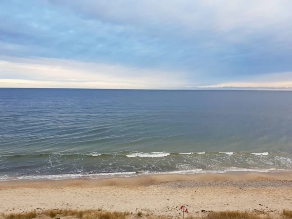 大海平静的泡沫般的波涛与背景为地平线的沙岸相遇 — 图库照片