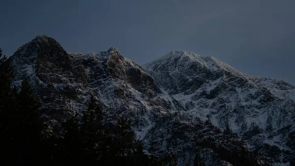 早朝の明け方の空の下で雪をかぶった山々の景色 — ストック写真
