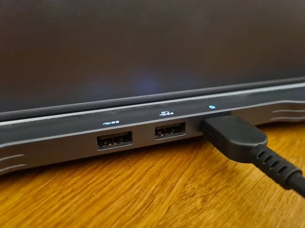 暗い灰色のラップトップのUsb出力と それに接続された黒いUsbのクローズアップショットライトブラウンテーブル — ストック写真