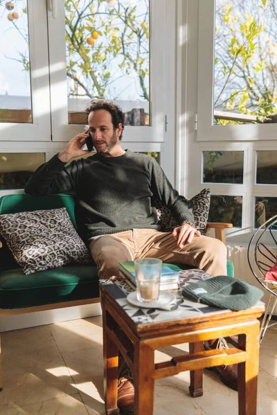一个白人男子坐在沙发上与电话交谈的垂直镜头 — 图库照片