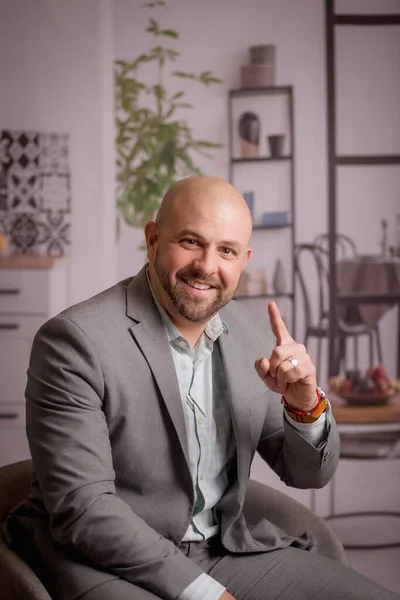 stock image A vertical shot of a smiling succesful businessman in a gray suit with his finger pointing up