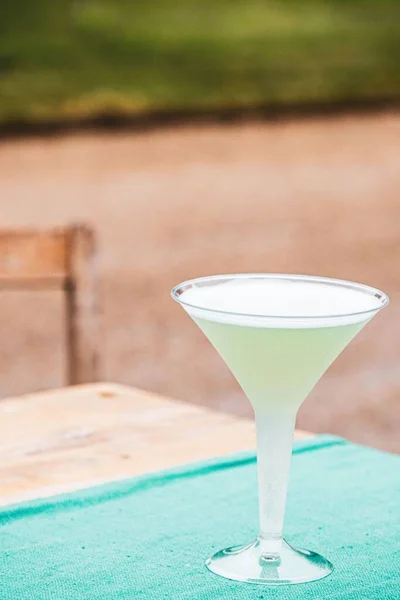 Colpo Verticale Bicchiere Cocktail Plastica Tavolo Con Sfondo Sfocato — Foto Stock