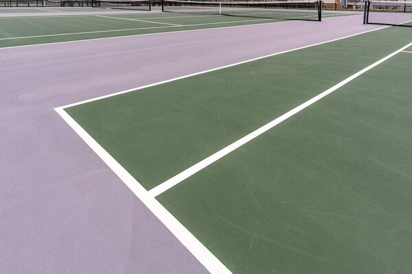 New outdoor green tennis courts with white lines.