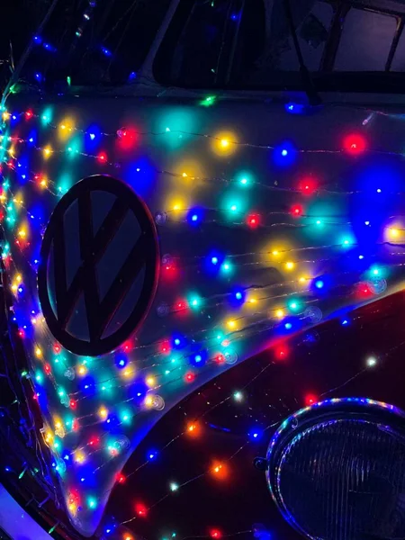 Vertikální Detailní Záběr Loga Volkswagen Vozidle Obklopeném Barevnými Vánočními Světly — Stock fotografie