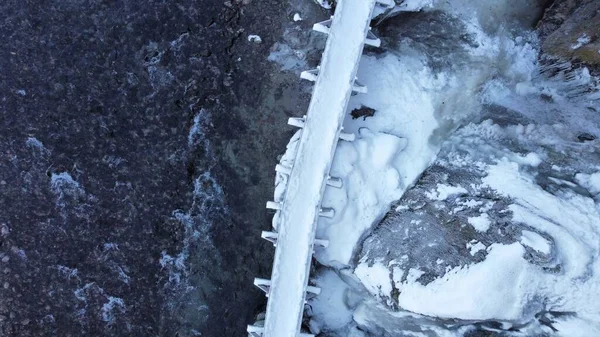 寒い冬の日に近くの雪と海の水に覆われた橋の空中トップビュー — ストック写真