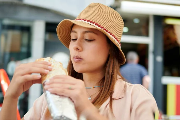 stock image A Hispanic woman eating a burrito in an open-air restaurant