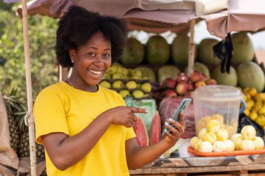 Mutlu bir Afrikalı kadın telefonunu kullanarak onu işaret ediyor.