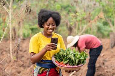Kadın Afrikalı çiftçi telefonunu kullanıyor.