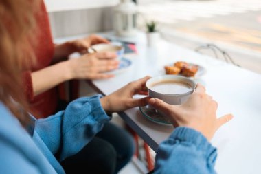 Kafede kahve içip kurabiye yiyen iki kadının yakın çekimi.