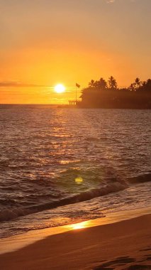 Gün batımında dalgalı bir denizin dikey görüntüsü.