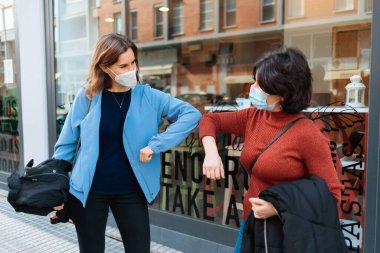 Dirseklerini çarpıştırarak birbirlerini selamlayan tıbbi maskeli insanlar. Salgın konsepti.