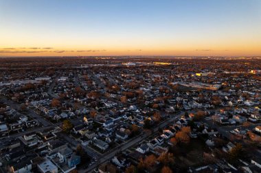 Gün doğumunda güzel altın bir gökyüzü olan Long Island üzerindeki havadan bir şehir manzarası.