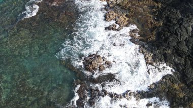 Yüksek açılı bir deniz dalgası sahilin kayalık sahiline çarpıyor.