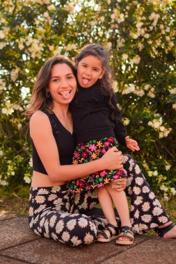 Annesiyle birlikte gün ışığında parkta poz veren bir çocuğun dikey çekimi.