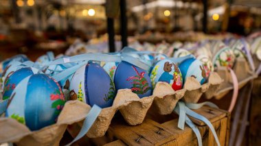 Mavi Paskalya yumurtalarından seçici bir poz, yumurta kutularında çizimler ve kurdeleler var.
