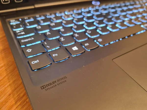 テーブルの上に黒いノートパソコンの青いライトのキーボードのクローズアップショット — ストック写真