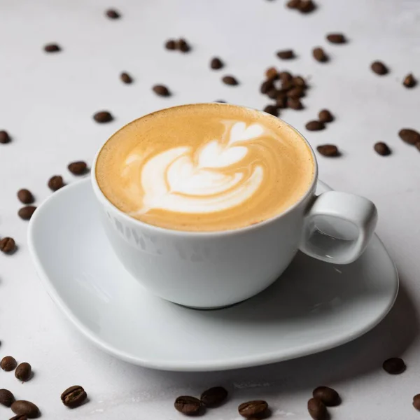 Eine Weiße Kaffeetasse Auf Einem Weißen Teller Umgeben Von Kaffeebohnen — Stockfoto