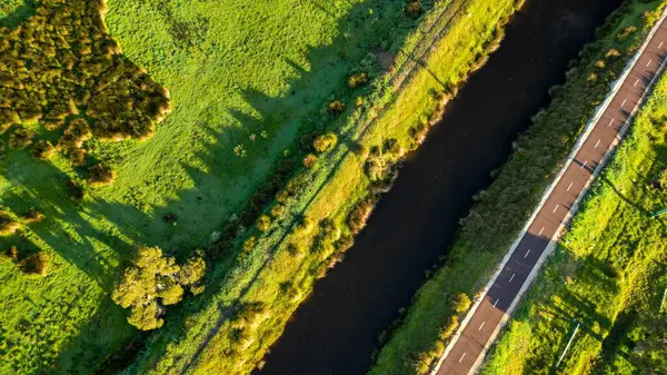 Drone Záběr Úzké Cesty Přiléhající Vodnímu Kanálu Zelených Polích Slunečného — Stock fotografie