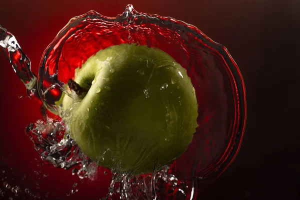 Agua Salpica Sobre Manzana Verde Sobre Fondo Rojo —  Fotos de Stock
