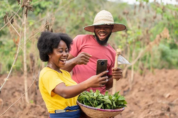 Heyecanlı Afrikalı çiftçiler telefona bakıyor. Heyecan verici haberler var.