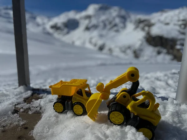 Leksakslastbilar Och Grävmaskiner Vintersnö Framför Ett Snöigt Berg Schweiziska Alperna — Stockfoto