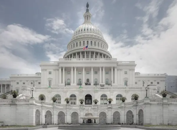 在蓝天的映衬下 美国国会大厦与华盛顿特区国旗的横向图片 — 图库照片