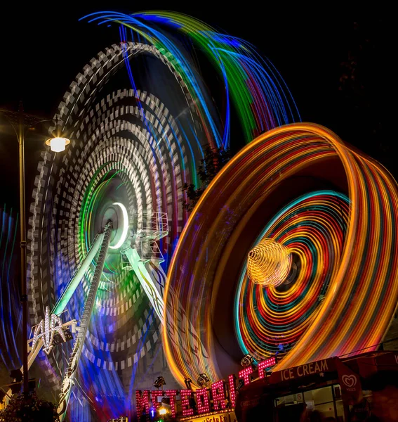 一个转弯轮的低角度运动模糊了夜间游乐园中的灯 — 图库照片
