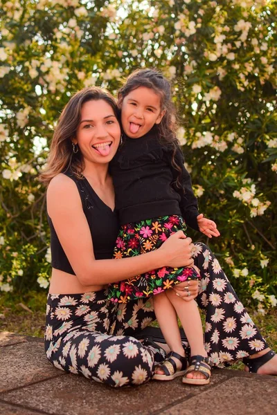 Annesiyle birlikte gün ışığında parkta poz veren bir çocuğun dikey çekimi.