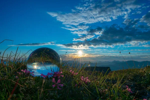明るい夕日と青い空がそれに反映されているフィールド上に横たわるクリスタルボール — ストック写真