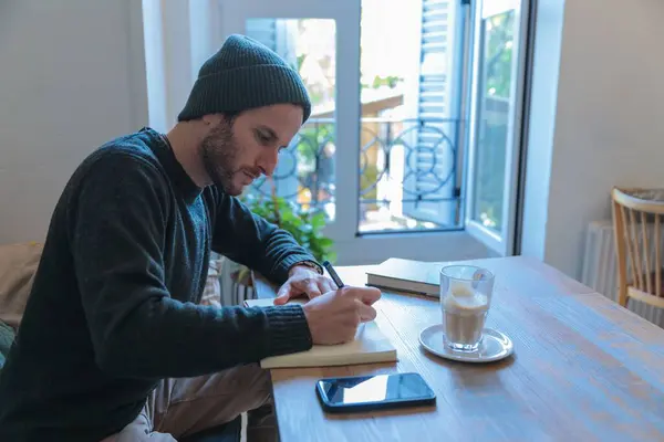 Seorang Pemuda Menulis Buku Catatan Dengan Kopi Atas Meja Kayu — Stok Foto