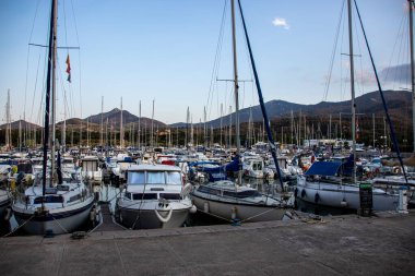 Fransa 'nın güneyinde, Argeles-sur-Mer marinasında demirlemiş bir dizi tekne, arka planda dağlarla çevrili bir şehir.