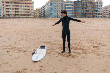 Beyaz bir erkek sörfçü okyanusta sörf yapmaya hazırlanıyor.