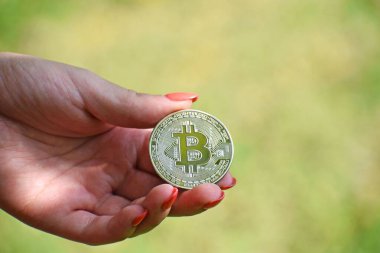 Bulanık arka planda gümüş bir bitcoin tutan bir kadın eli - kripto para kavramı