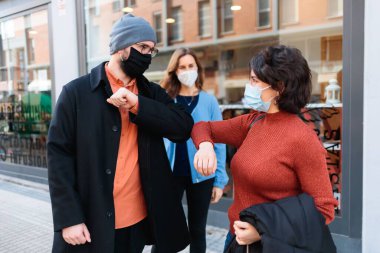 Dirseklerini çarpıştırarak birbirlerini selamlayan tıbbi maskeli insanlar. Salgın konsepti.