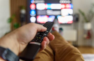 Bir erkeğin elindeki uzaktan kumandanın yakın çekim görüntüsü.