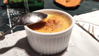 Masanın üzerinde Creme Brulee kasesinin üzerinde gümüş bir kaşık var.