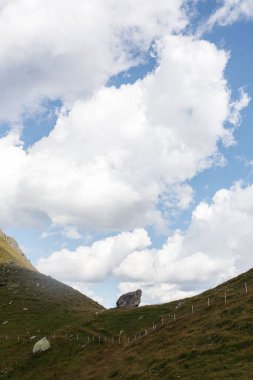 Bulutlu bir gökyüzüne karşı dağlarla yeşil bir manzaranın dikey görüntüsü