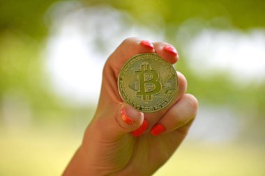 Bulanık arka planda gümüş bir bitcoin tutan bir kadın eli - kripto para kavramı