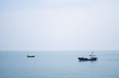 Sisli bir deniz manzarasına karşı iki tekne