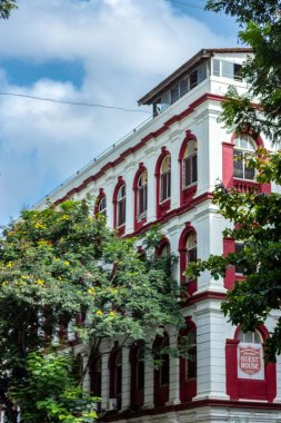 Beyaz duvarları ve kırmızı balkonları olan bir misafir evinin dikey çekimi.