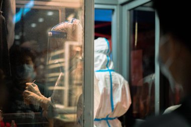 Koruyucu kostümlü bir adamın analiz etmesi.