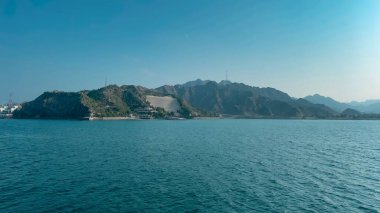 Fujairah, BAE 'nin yeşil dağlarına karşı durgun mavi denizin kuş bakışı görüntüsü
