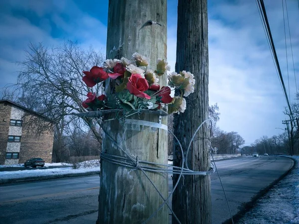 在街上的一根木制柱子上挂着一束美丽的人造红白玫瑰 — 图库照片
