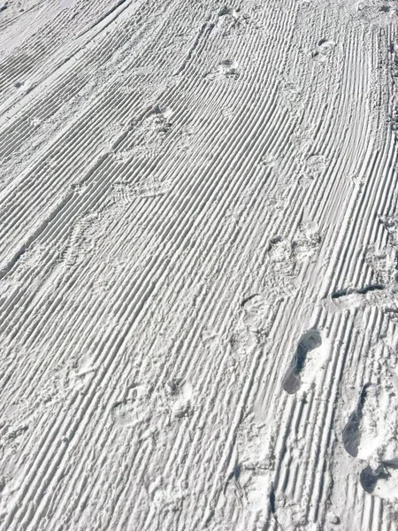 Eine Vertikale Nahaufnahme Des Sonnenbeschienenen Schnees Fließt Mit Schritten Auf — Stockfoto