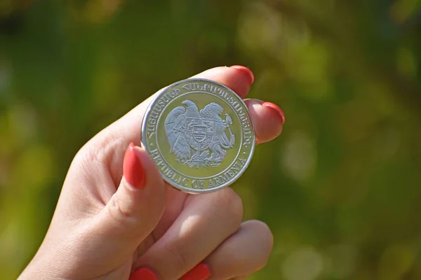アルメニアの紋章入りの硬貨を手に持っている女性の手の近くで背景がぼやけている — ストック写真
