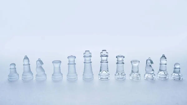 Eine Reihe Gläserner Schachfiguren Hintereinander Auf Weißem Hintergrund Mit Kopierraum — Stockfoto