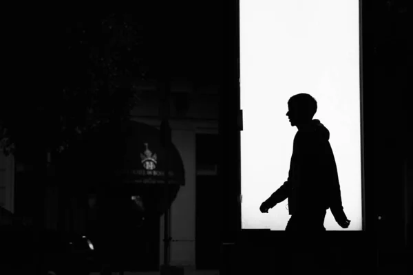 stock image A black silhouette of a guy walking in front of an open door in a building