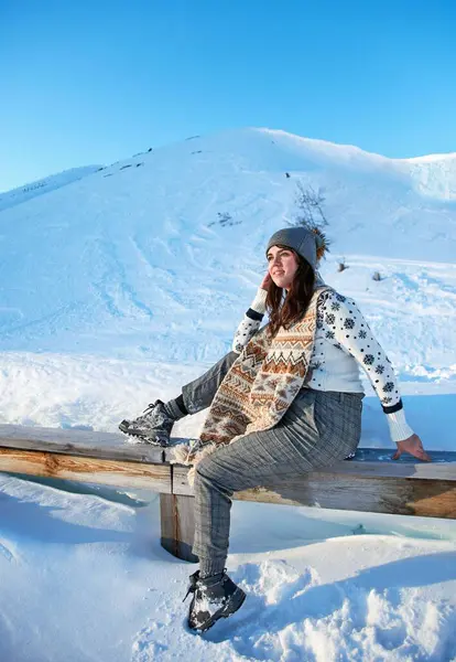冬の帽子とスカーフの女性観光客は 雪の山のベンチから美しい景色を眺める — ストック写真