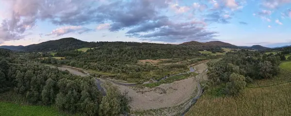 ポーランドの村で曇りの空の下で木々や山と緑の風景の中に狭い川のパノラマビュー — ストック写真